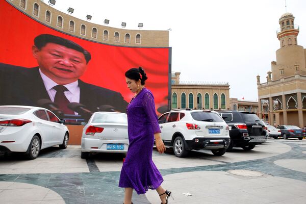 Женщина у гигантского экрана на главной городской площади в Кашгаре, Синьцзян-Уйгурский автономный район, Китай - Sputnik Таджикистан