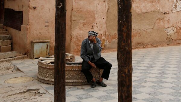 Пожилой мужчина закрывает лицо от камеры в Кашгаре, Синьцзян-Уйгурский автономный район, Китай - Sputnik Тоҷикистон