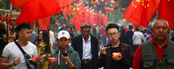 Люди проходят мимо китайских флагов в Кашгаре, Синьцзян-Уйгурский автономный район, Китай - Sputnik Таджикистан