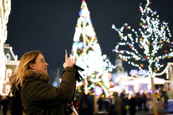 Девушка фотографирует украшенную новогодними огнями Красную площадь в Москве - Sputnik Таджикистан