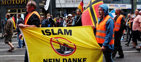 Участники акции против проиммигрантской политики канцлера Германии Ангелы Меркель в Берлине - Sputnik Таджикистан