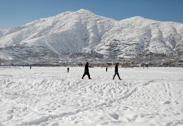 Афганские мужчины гуляют после первого снега зимой по заснеженной земле в Кабуле - Sputnik Таджикистан