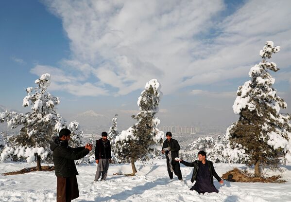 Афганская молодежь фотографирует друг друга после первого снега зимой на заснеженной земле в Кабуле - Sputnik Таджикистан