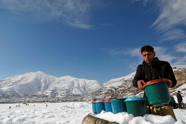 Афганец из Кабула готовит ведра йогурта на заснеженной земле для продажи - Sputnik Таджикистан