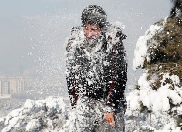Афганский мужчина играет с друзьями во время первого снега зимой в Кабуле - Sputnik Таджикистан