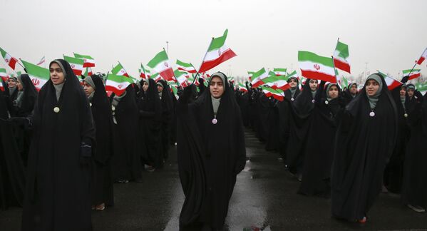 Школьницы машут иранскими флагами во время мероприятия, посвященного 40-й годовщине Исламской революции, на площади Азади в Тегеране - Sputnik Таджикистан