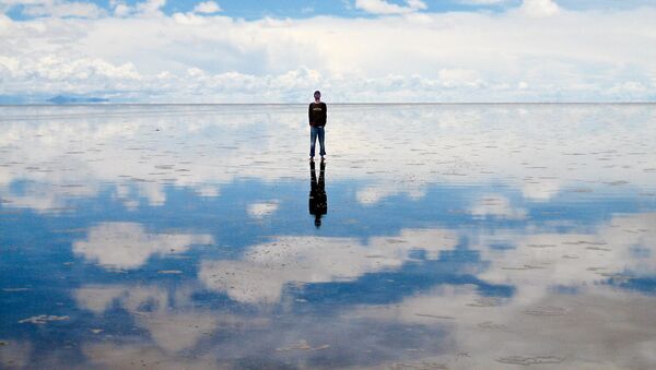 Турист на соленом озере Салар де Уюни, когда оно покрыто водой и отражает небо - Sputnik Таджикистан