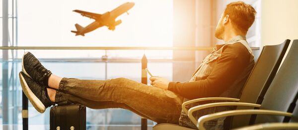 Молодой человек в аэропорту в зале ожидания - Sputnik Тоҷикистон