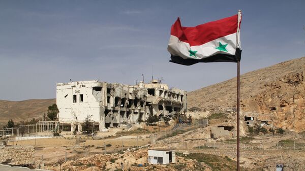Сирийский флаг на фоне разрушенного дома в сирийском городе Маалюля - Sputnik Тоҷикистон