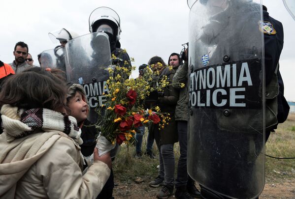 Дети дарят цветы сотрудникам греческой полиции после столкновений у лагеря беженцев в Диавате, Греция - Sputnik Таджикистан