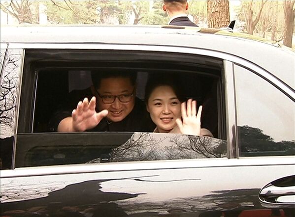 Лидер Северной Кореи Ким Чен Ун (слева) и его жена Ри Сол Чу (справа), машущие на прощание - Sputnik Таджикистан