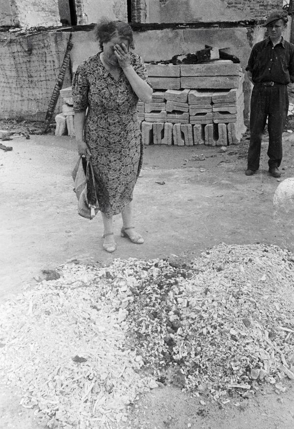 Женщина плачет у праха сожженных людей в печах лагеря смерти Майданека в польском Люблине, 1944 год - Sputnik Таджикистан