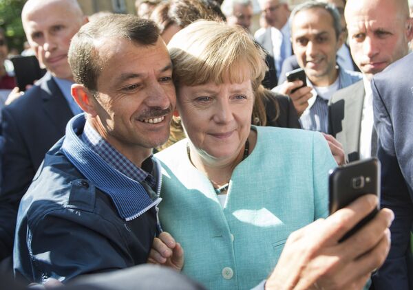 Беженец делает селфи с канцлером Германии Ангелой Меркель во время ее визита в центр для новоприбывших беженцев в Берлине - Sputnik Таджикистан