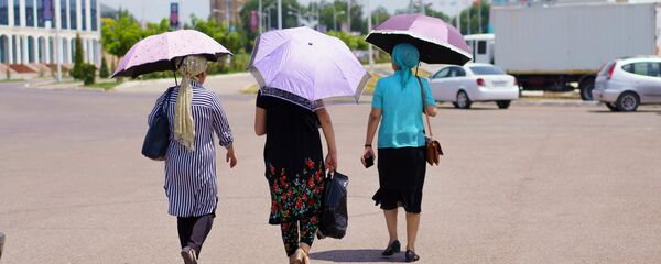 Женщины идут с зонтиками спасаясь от солнца Женщины идут с зонтиками спасаясь от солнца - Sputnik Тоҷикистон