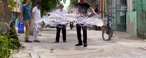 Мужчина разливает воду на тротуар - Sputnik Тоҷикистон