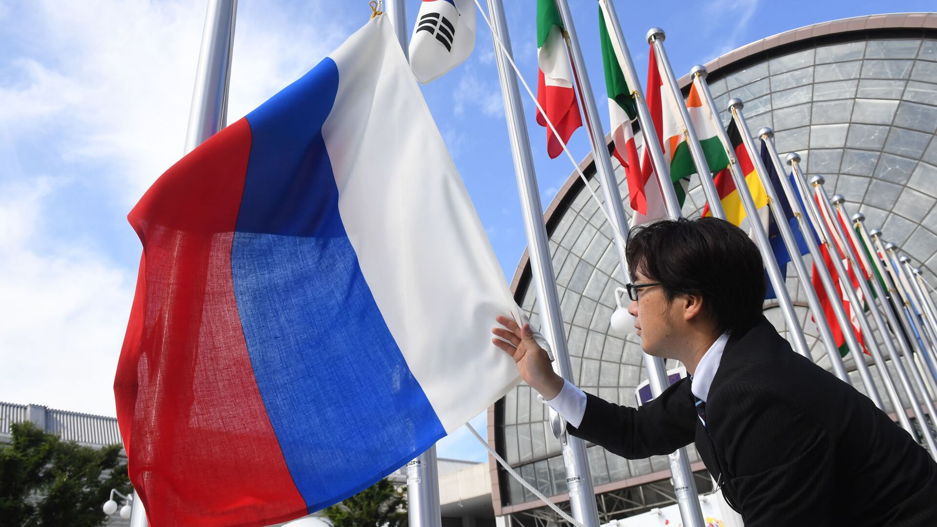 Вывешивание флага России у международного выставочного центра INTEX Osaka перед открытием саммита Группы двадцати в японской Осаке - Sputnik Таджикистан, 1920, 22.07.2022