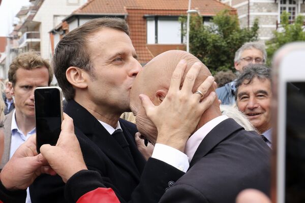 Президент Франции Эммануэль Макрон целует сторонника после голосования на выборах в европарламент в Ле-Туке на севере Франции - Sputnik Таджикистан