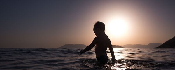 Ребенок в воде на закате, архивное фото - Sputnik Тоҷикистон