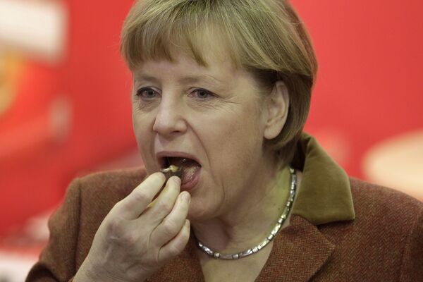 Канцлер Германии Ангела Меркель во время поедания кусочка шоколада  - Sputnik Таджикистан