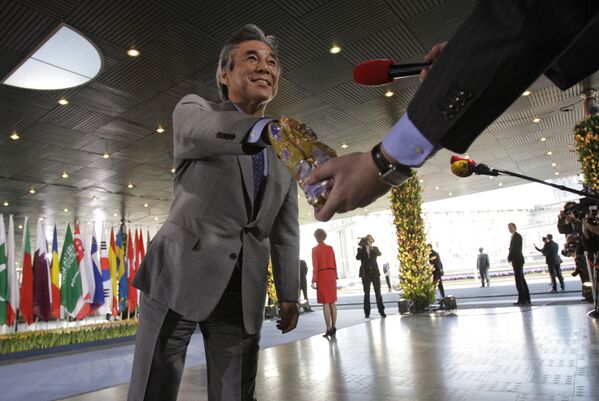 Министр иностранных дел Японии Хирофуми Накасонэ берет шоколадку из пакета репортера голландского телеканала на конференции в Гааге, Нидерланды - Sputnik Таджикистан