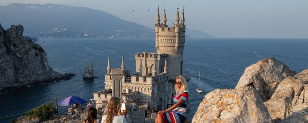 Отдыхающие фотографируются возле замка Ласточкино гнездо на береговой скале в поселке Гаспра в Крыму - Sputnik Таджикистан