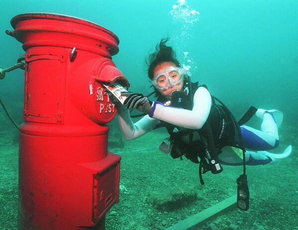 Водолаз кладет пластиковое письмо в почтовый ящик, установленный на глубине 10 метров на дне моря у берегов Сузами в префектуре Вакаяма - Sputnik Таджикистан