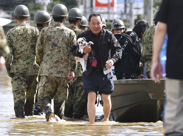 Местный житель со своей собакой эвакуируется из зоны, затопленной рекой Абукума, префектура Фукусима, Япония - Sputnik Таджикистан