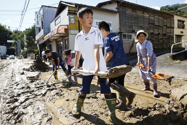 Школьники и жители города убирают грязь после наводнения, вызванного тайфуном Хагибис в Марумори, префектура Мияги, Япония - Sputnik Таджикистан