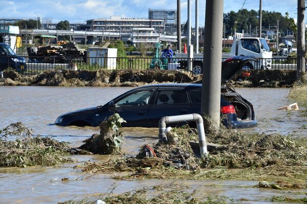 Автомобиль стоит на территории, затопленной в результате тайфуна Хагибис в Хигаси-мацуяме, префектура Сайтама, Япония - Sputnik Таджикистан