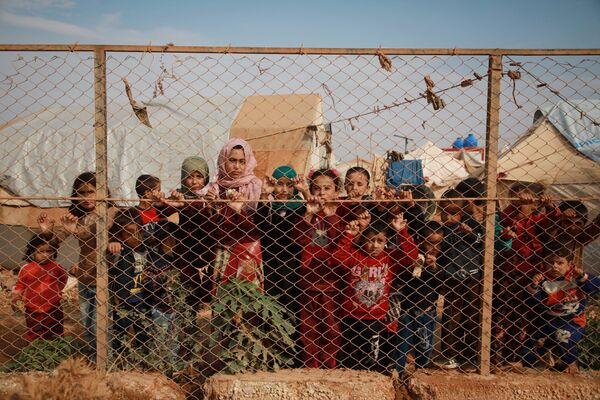 Сирийские дети у забора палаточного лагеря недалеко от деревни Кафр-Лусин, Сирия - Sputnik Таджикистан