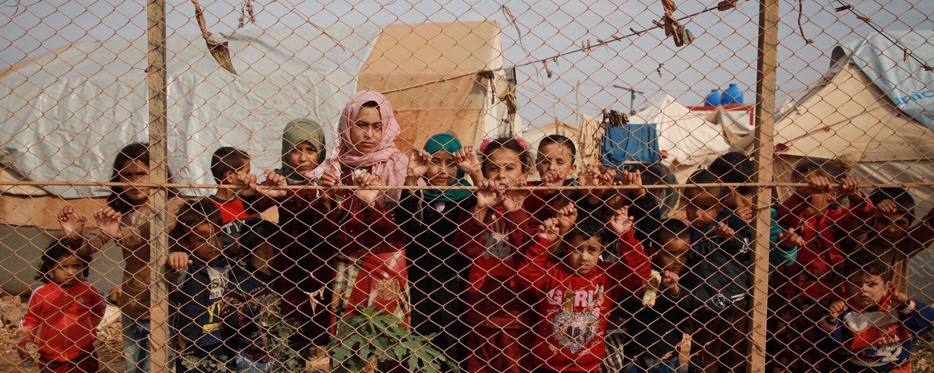 Сирийские дети у забора палаточного лагеря недалеко от деревни Кафр-Лусин, Сирия - Sputnik Таджикистан, 1920, 08.02.2021