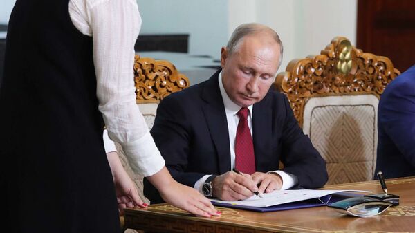 Президент РФ Владимир Путин подписывает документ, архивное фото - Sputnik Тоҷикистон