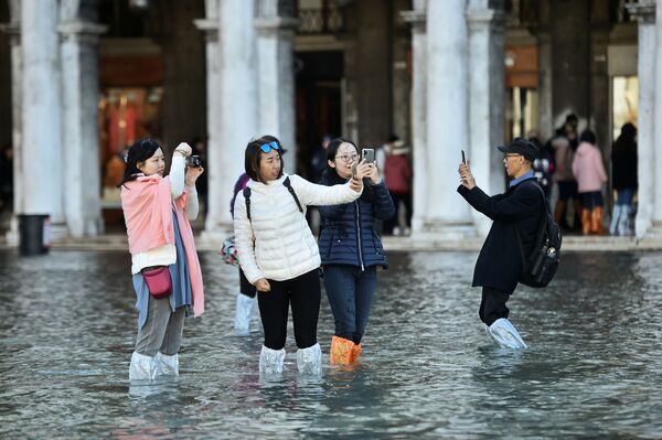Туристы фотографируются на площади Сан-Марко во время наводнения в Венеции - Sputnik Таджикистан
