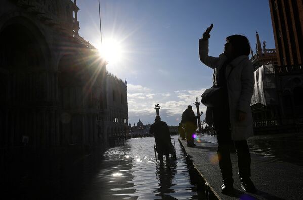 Турист на площади Сан-Марко во время наводнения в Венеции - Sputnik Таджикистан