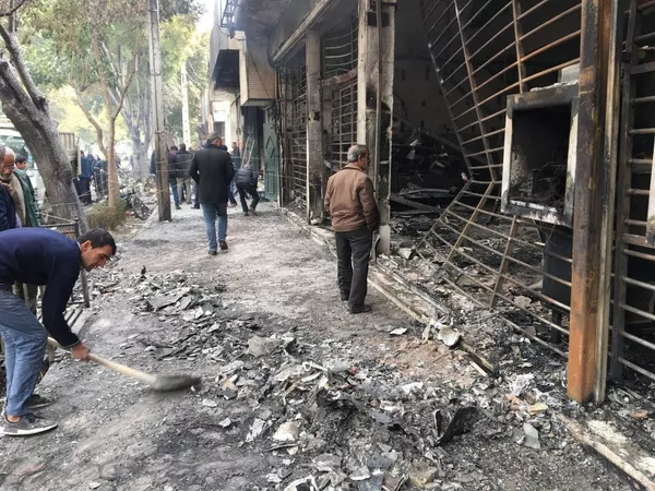 Прохожие у сожженного здания банка после протестов в Эсфахане 