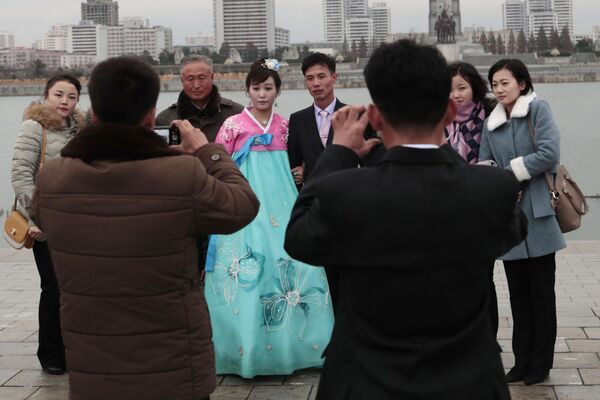 Молодожены во время свадебной фотосессии со своими родственниками в Пхеньяне - Sputnik Таджикистан
