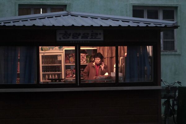 Продавец в киоске с закусками и напитками в Пхеньяне - Sputnik Таджикистан