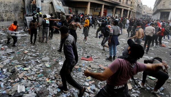 Иракские демонстранты бросают камни в иракские силы безопасности во время продолжающихся антиправительственных акций протеста в Багдаде, Ирак  - Sputnik Тоҷикистон