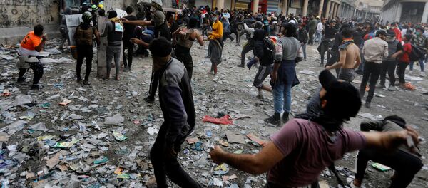 Иракские демонстранты бросают камни в иракские силы безопасности во время продолжающихся антиправительственных акций протеста в Багдаде, Ирак  - Sputnik Тоҷикистон