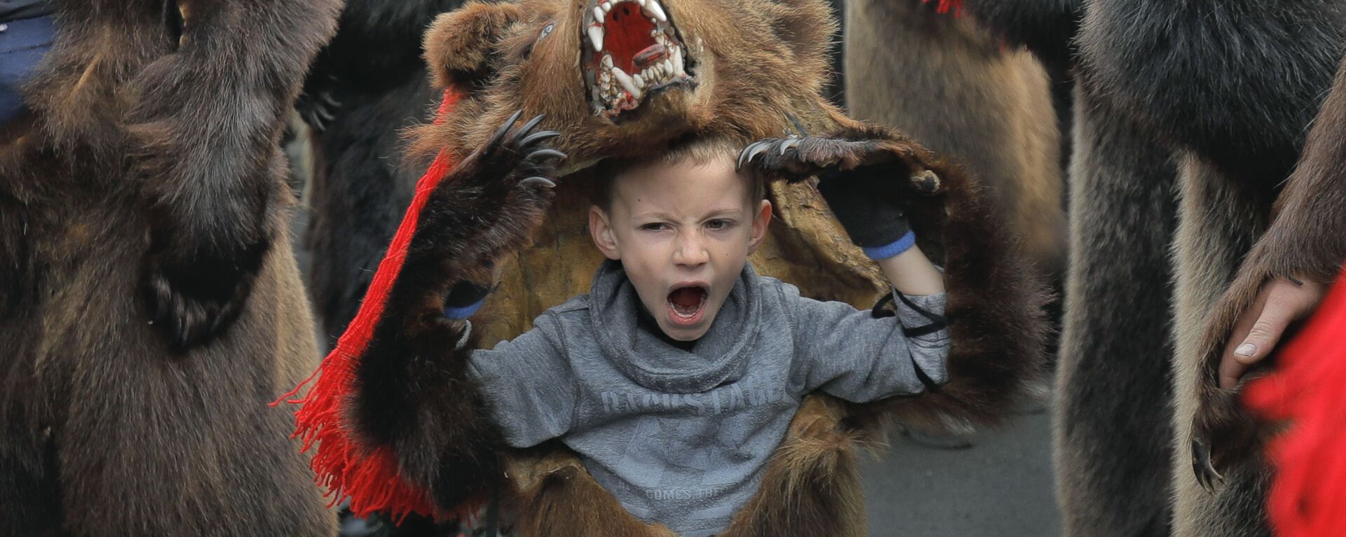 Зевающий мальчик в костюме медведя на новогоднем шествии в румынском городе Комэнешти - Sputnik Таджикистан, 1920, 31.12.2019