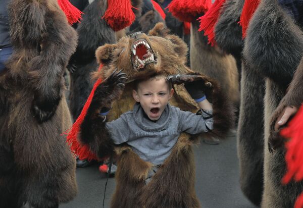 Зевающий мальчик в костюме медведя на новогоднем шествии в румынском городе Комэнешти - Sputnik Таджикистан