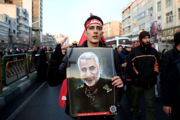 Мужчина несет фотографию Касема Сулеймани во время траурного шествия в Тегеране  - Sputnik Таджикистан