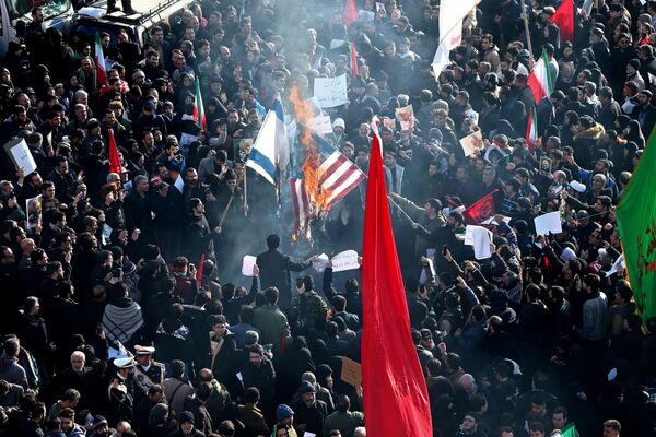 Иранский народ сжигает флаги США и Израиля во время траурного шествия по случаю прощания с иранским генералом Касемом Сулеймани - Sputnik Таджикистан