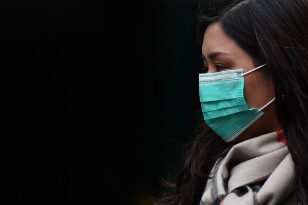 Девушка в медицинской маске в районе Чайна-таун в Лондоне - Sputnik Тоҷикистон