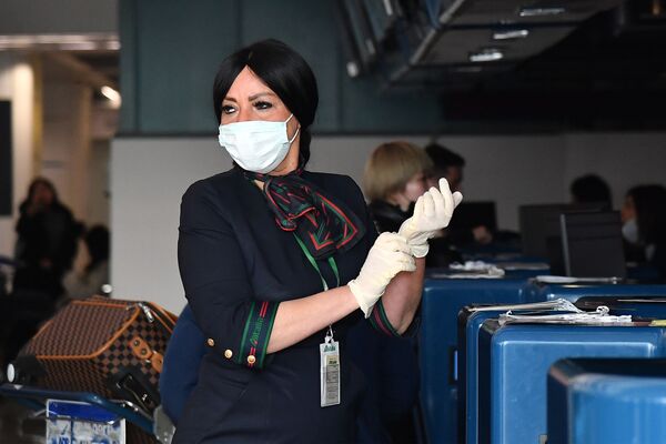 Сотрудница аэропорта в маске и перчатках до проверки пассажиров в Риме  - Sputnik Тоҷикистон