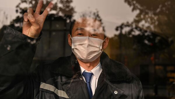 Охранник отеля в маске в китайском городе Ухань  - Sputnik Таджикистан