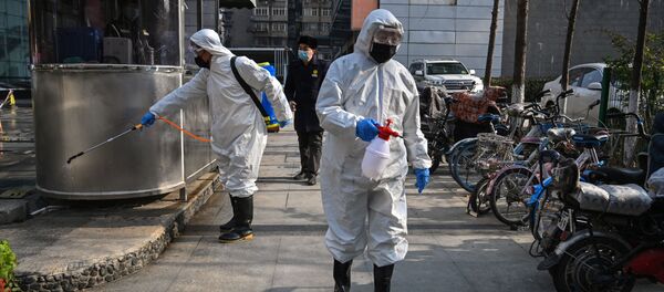 Люди, одетые в защитную одежду, дезинфицируют область в Ухане - Sputnik Тоҷикистон