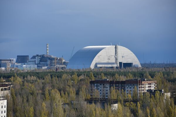 Вид на новый безопасный конфайнмент и саркофаг на 4-м энергоблоке Чернобыльской атомной электростанции из города Припять - Sputnik Таджикистан