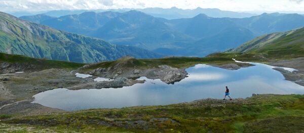 Путешественник проходит мимо горного водоема на Аляске - Sputnik Таджикистан