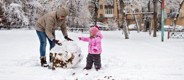 Женщина с ребенком лепят снеговика - Sputnik Таджикистан